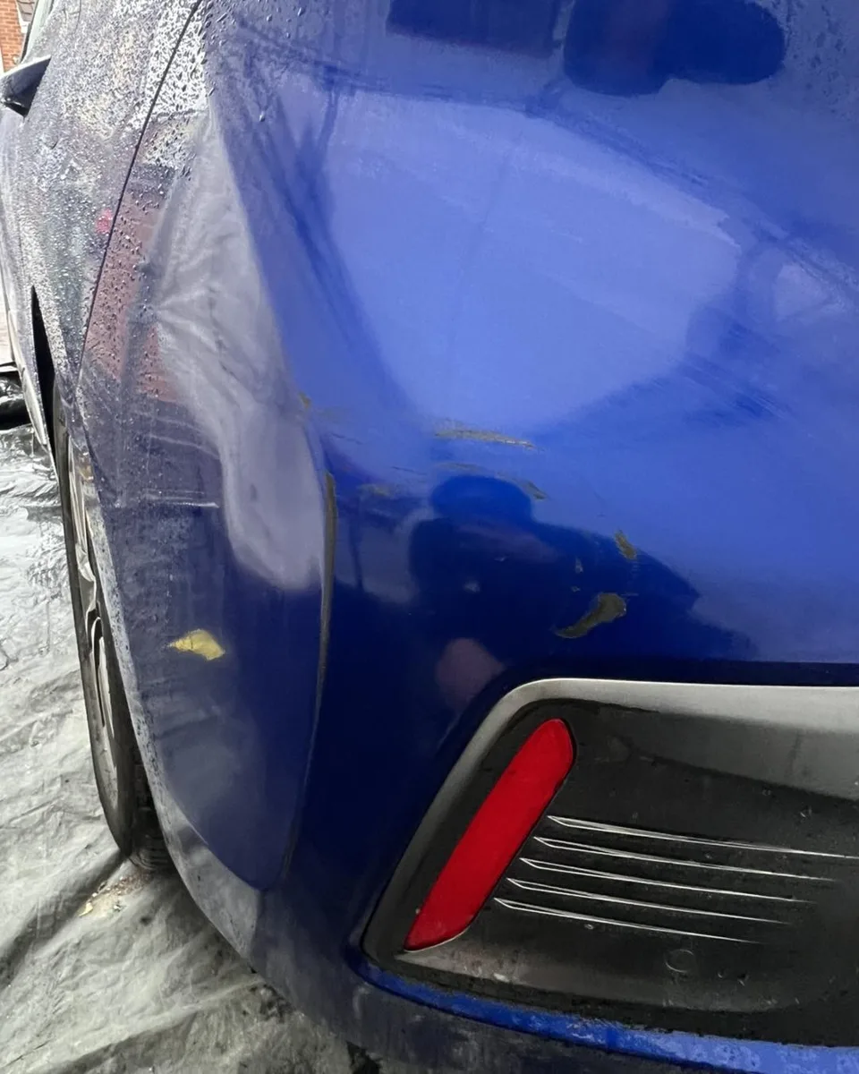 Scratched blue rear bumper beside the reflector