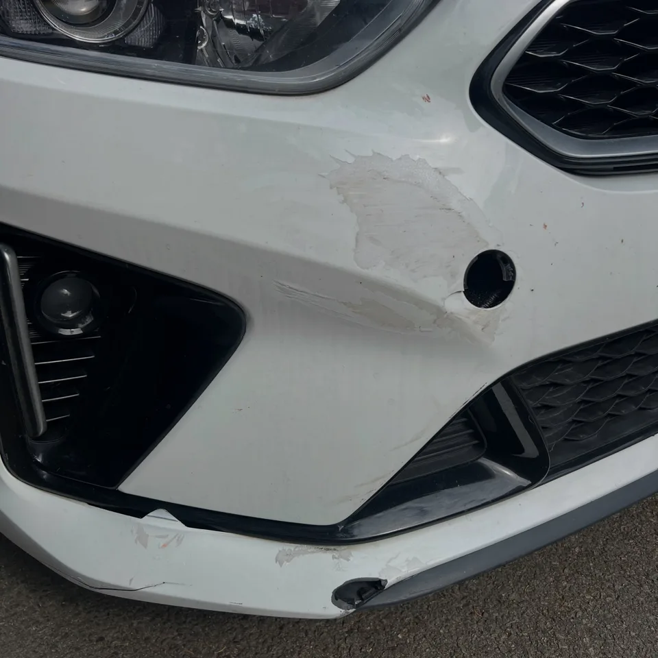 Scuffed white front bumper beside the fog light